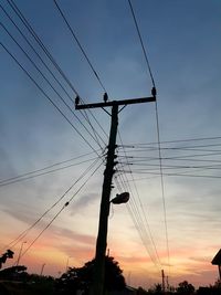 Low angle view of silhouette electricity pylon against sky during sunset