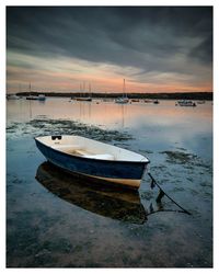 Boats moored in sea against sky during sunset