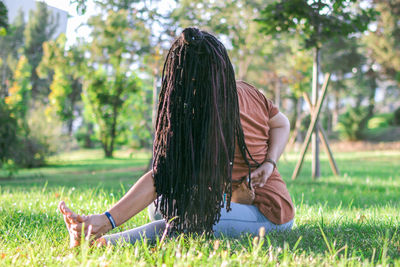 Woman with long african braids is doing yoga outside in a park. concept of healthy lifestyle.