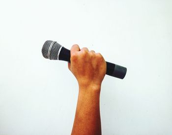 Close-up of hand holding camera against white background