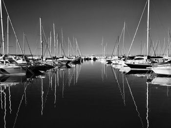 Boats moored in harbor against clear sky