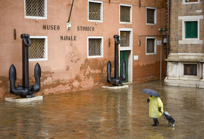 High angle view of person walking with luggage on wet street at piazza san marco