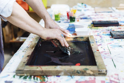 Crop artisan transferring ink on fabric with silkscreen