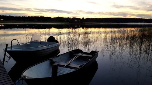 Boat moored in lake against sky during sunset