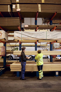 Multiracial female colleagues with planks on rack discussing while working in lumber industry