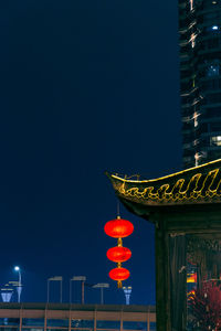 Low angle view of lantern hanging on illuminated building against sky at night