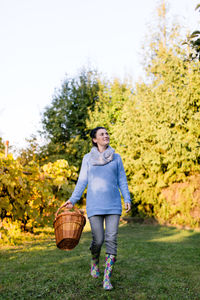 Happy beautiful woman walking with basket at orchard