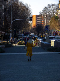 Rear view of woman walking on road in city