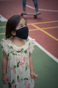 Portrait of toddler wearing reusable black face mask in outdoor.