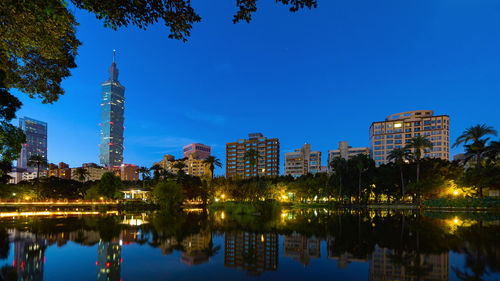 Reflection of buildings in lake against blue sky