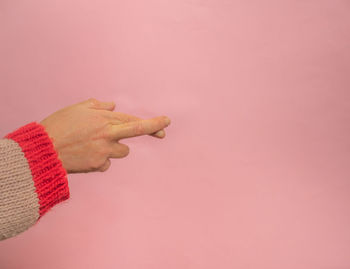 Close-up of hand holding pink flowers against gray background