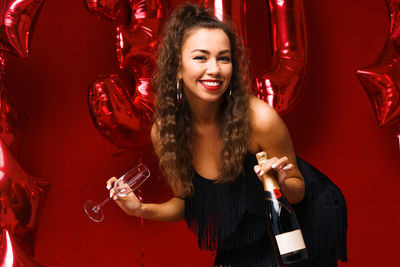 Beautiful woman posing on a red background with balloons