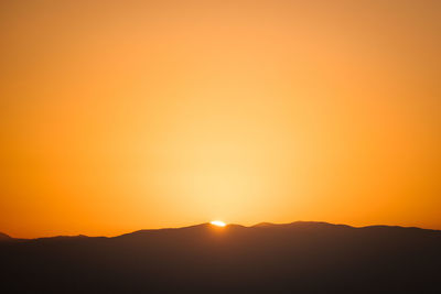 Scenic view of silhouette mountains against orange sky