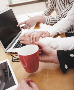 Midsection of woman holding coffee cup on table