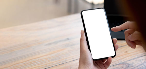 Close-up of person using mobile phone on table