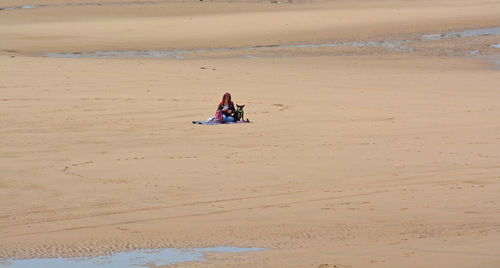 Distant view of mature woman sitting at beach