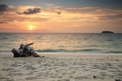 Seascape at sunrise with tree root on white sand beach at adang island near koh lipe