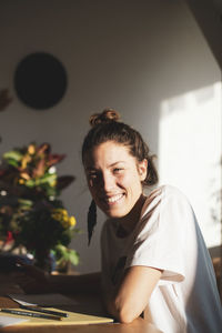 Beautiful natural young woman sits and writes smiling in warm sunlight