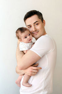 Happy father hugging cute baby and looking at camera