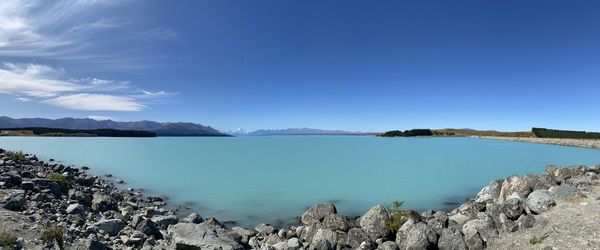 Panoramic view of sea and mountains against blue sky