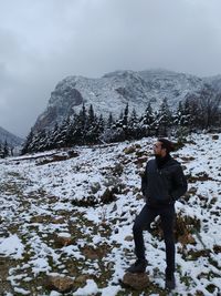 Full length of man standing on snowcapped mountain against sky