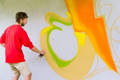 Rear view of man making graffiti on wall