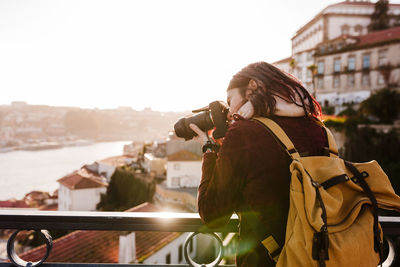 Woman in porto bridge taking pictures with camera at sunset. tourism in city europe. travel