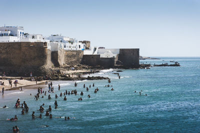 People swimming in sea against clear sky