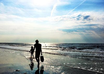 Silhouette men on beach against sky