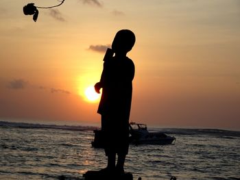 Silhouette man standing at beach during sunset