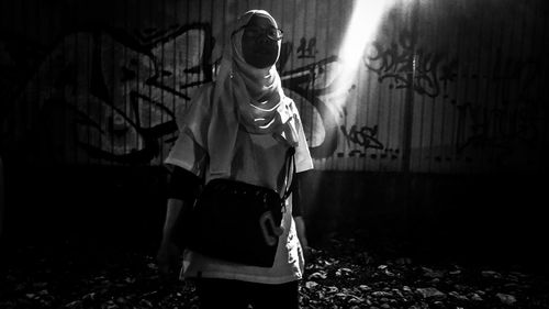 Woman standing against graffiti wall