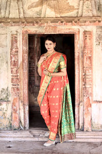 Full length of young woman wearing sari standing against old building