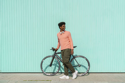 Young man riding bicycle standing against wall