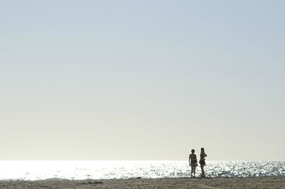 People on beach against clear sky