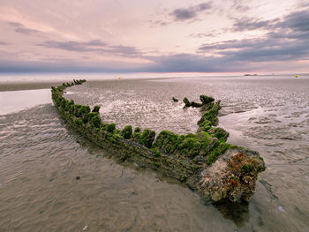 Wreck of a hull from a world war ship at a beach in northern france at sunrise