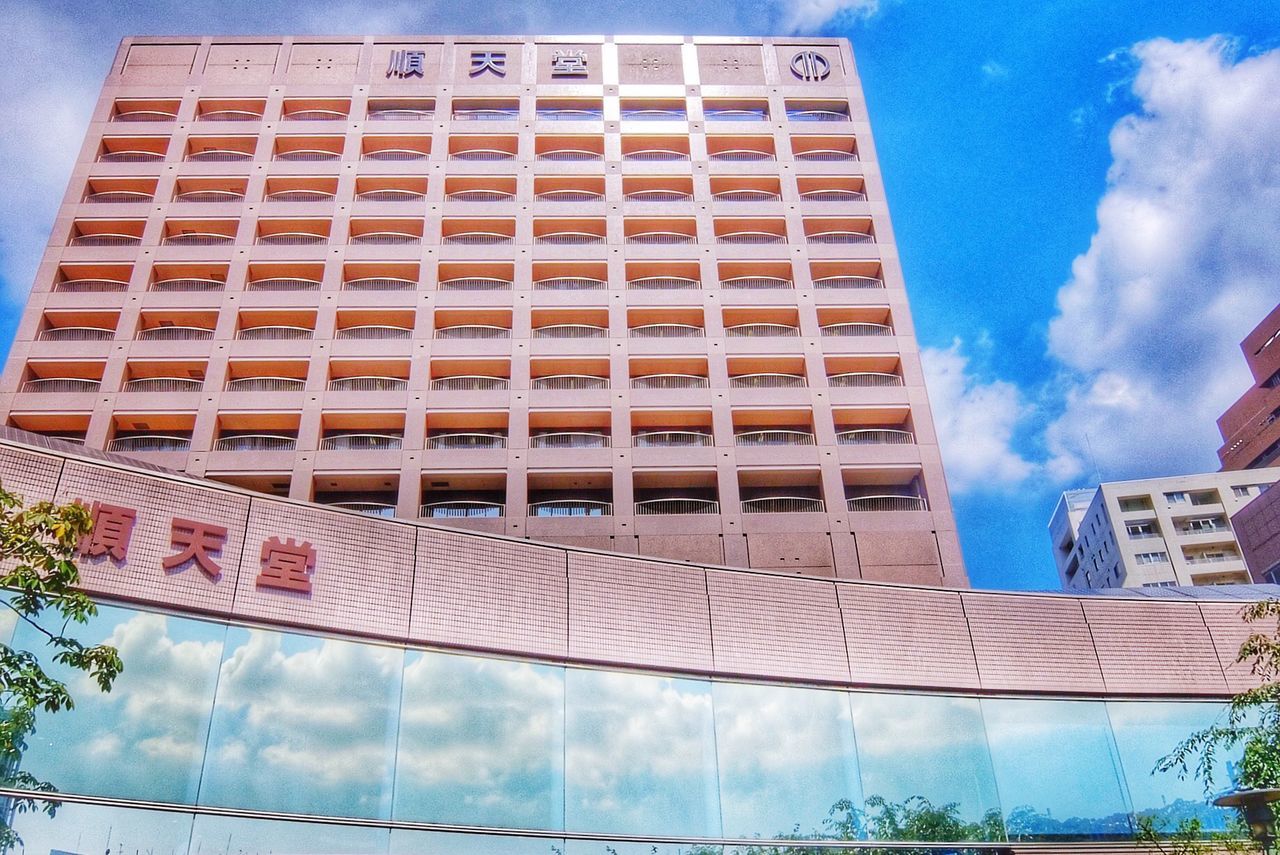 architecture, building exterior, built structure, low angle view, sky, building, blue, day, city, cloud - sky, outdoors, text, modern, no people, window, cloud, glass - material, facade, pattern, wall - building feature