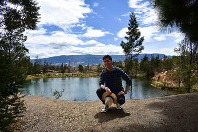 Full length of man sitting on lake against sky