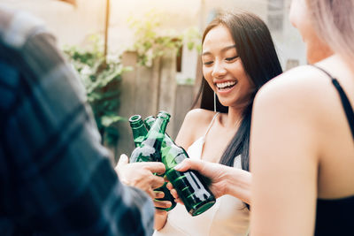 Cheerful friends toasting beer bottles at backyard