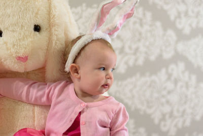 Cute baby girl playing with stuffed toy at home