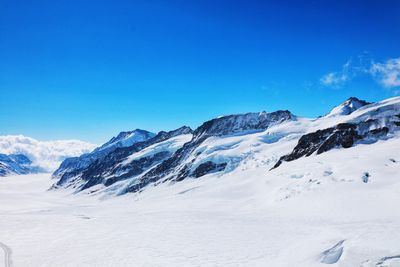 Scenic view of snowcapped mountains against blue sky