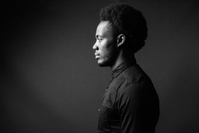 Portrait of young man against black background