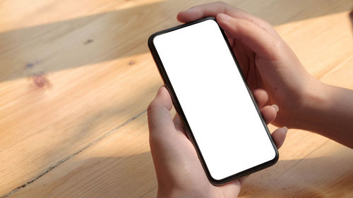 Midsection of person using mobile phone on table