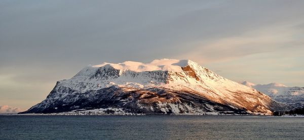 Scenic view of snowcapped mountains by sea against sky