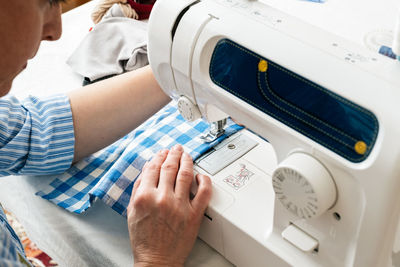 High angle view of craftswoman sewing textile on machine at workshop