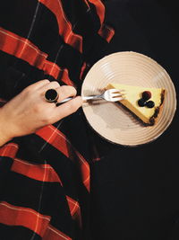 Cropped hand of woman eating pastry in plate