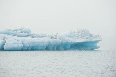 Frozen sea against sky during winter