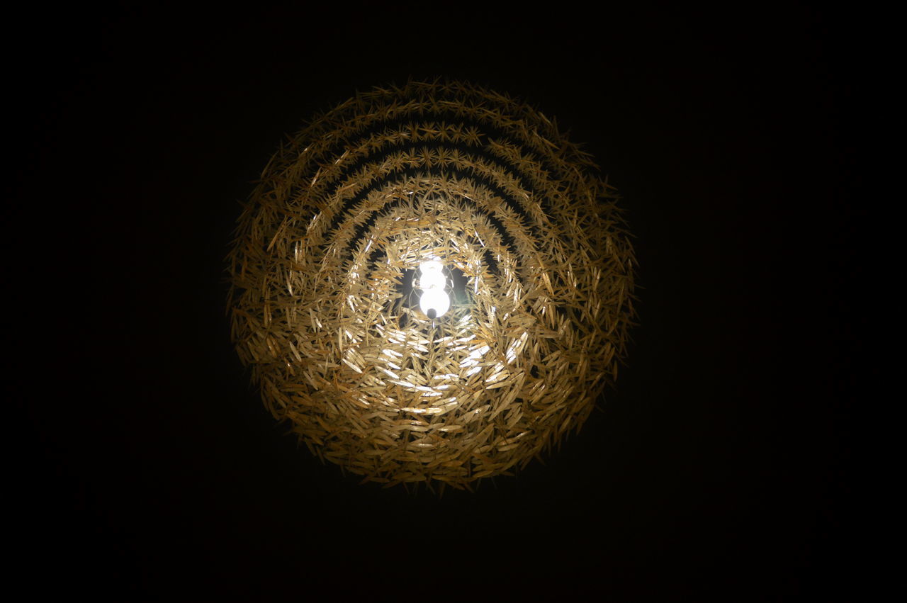 LOW ANGLE VIEW OF ILLUMINATED LAMP IN DARKROOM AGAINST BLACK BACKGROUND