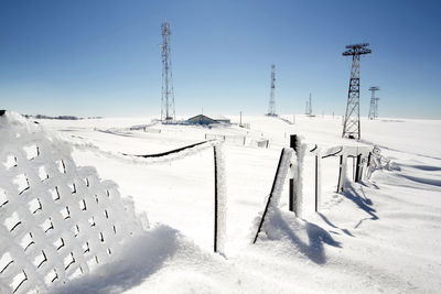 Snow covered damaged fence on field against sky