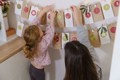 Toddler child gets new advent calendar task, waiting for christmas. festive mood for cute curly girl