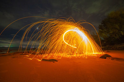 Light trails on beach against sky at night